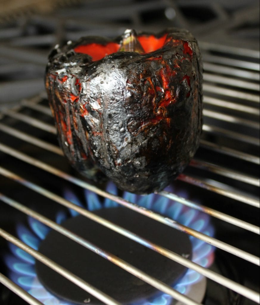 roasting a red pepper over a gas stove. 